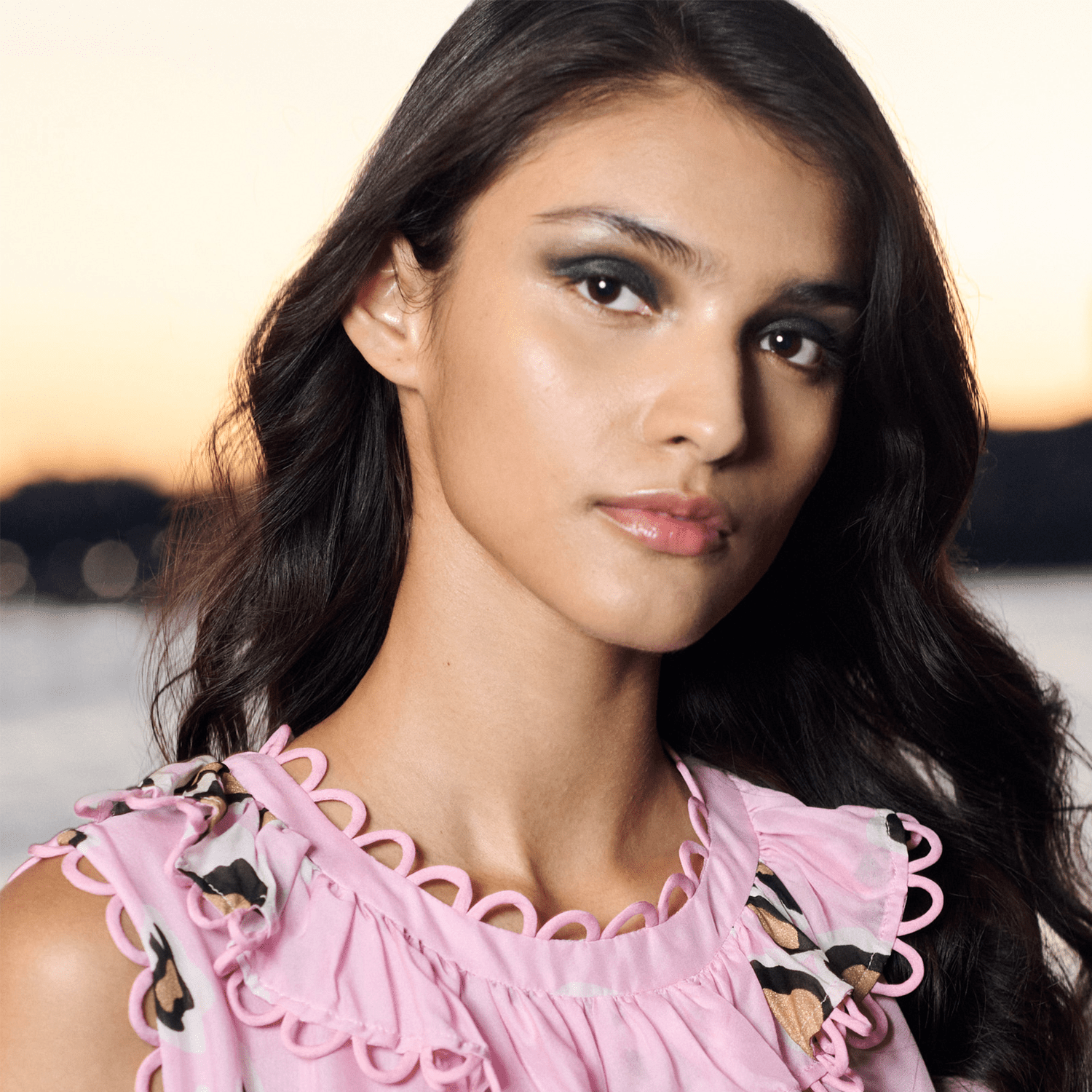 Model in a pink shirt and shimmery green eyeshadow