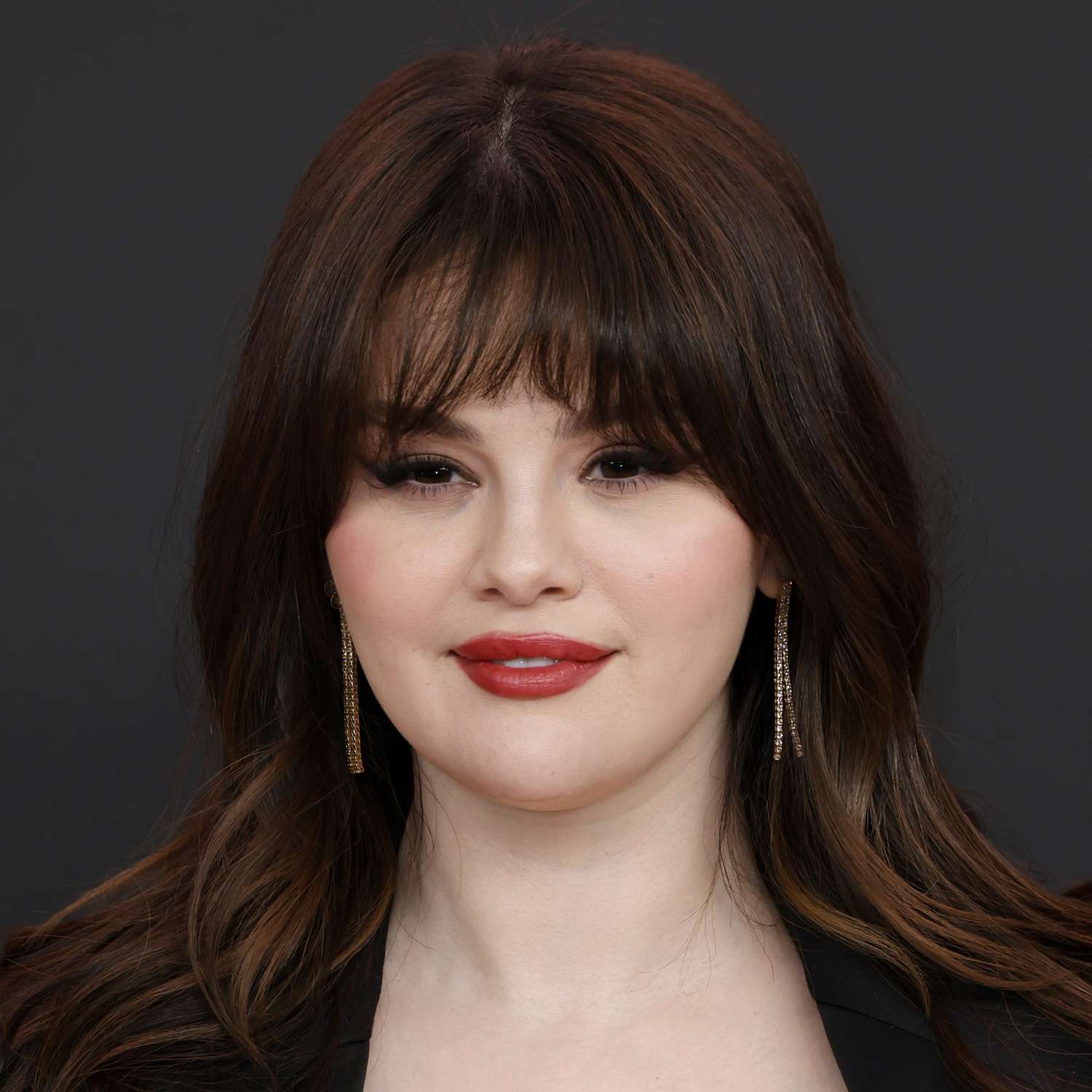 Selena Gomez wears french girl bangs with a blow out and red-orange lip at an LA premiere